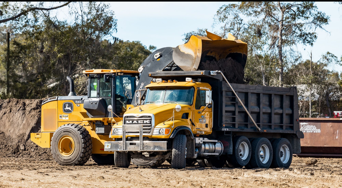 John Deere wheel loader dumping into Mack dump truck on job site